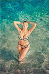 Sexy young woman in bikini standing in water, hands behind head, Dubrovnik, Croatia
