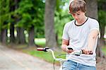 Young man with bicycle using mobile phone, Osijek, Croatia