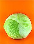 Fresh green cabbage on orange background .