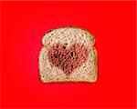 toasted bread slice with  heart shape  on red background.
