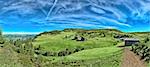 Italian mountain panorama in South Tyrol with chalet, dairy cows and green pastures on a sunny day.