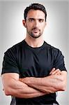 Personal trainer with is arms crossed, in a grey background