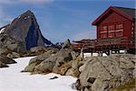 Mountain cabin on Lofoten islands in Norway with sharp mountain peak towering above