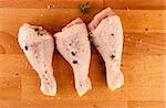 Chicken drumsticks on a wooden board with herbs