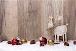 christmas decoration with wood background, snow, elk, christmas baubles gold and red and pine cones