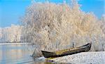 Frosty winter trees and boat near Danube river