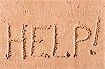 on the wet sand written the word "Help!" by the sea