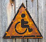 Disabled Icon on Weathered Triangular Yellow Warning Sign. Grange Background.
