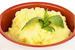 Classical Mashed Potato in Bowl Garnished with Green Basil Leafs closeup on white background