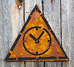 Icon of Clock Face on Weathered Triangular Yellow Warning Sign. Grange Background.