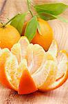 Fresh Ripe Tangerine Full Body with Leafs and  Segments with Citrus Peel closeup on Wooden background