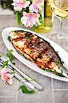 Baked sea bream and glass of white wine on the table