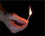 adult man hand holding matchstick in the dark