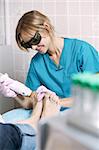 Podiatrist doing a foot laser treatment on a woman to kill fungal infections of the nail, remove unwanted hair and rejuvenate the skin