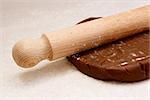 Closeup of wooden rolling pin on gingerbread cookie dough