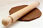 Wooden rolling pin being used to roll out gingerbread cookie dough