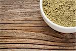 kelp powder nutritional supplement reach in Iodine, Calcium, Iron, Potassium, Vitamin B1, B2, B12 and polysaccharides - ceramic bowl on grained wood
