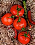 Fresh Ripe Tomatoes with Stems and Chili Peppers closeup on Burlap background. Top View