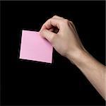 adult man hand holding sticky note, isolated on black