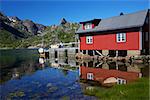 Typical red modern fishing hut on Lofoten islands in Norway reflecting in fjord