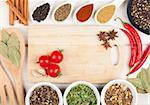 Colorful herbs and spices selection. Aromatic ingredients on wood table with cutting board for copyspace
