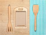 Kitchen utensils with notepad for copy space on wooden table