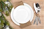 Empty plate, silverware set and christmas tree on wooden table