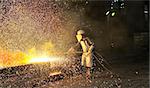 worker using torch cutter to cut through metal shoot in a plant