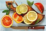 Fresh citrus fruit with leaves on an kitchen cutting board.