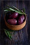 Olives in wooden bowl with rosemary.