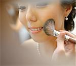 Beautiful Asian bride applying wedding make-up, candid photo.