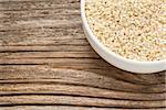 unhulled sesame seeds - a ceramic bowl on grained wood background