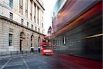 Red Bus in motion in City of London on contemporary buildingd