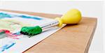 green paint with paint brush  and paper on wooden table