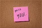 pink reminder sticky note on cork board miss you phrase