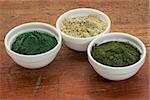 kelp, chlorella and Hawaiian spirulina powders - nutritional supplements from a sea - ceramic bowls against grunge wood