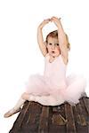 Little ballet girl wearing a pink tutu on an antique trunk