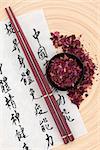 Chinese herbal medicine peony flower petals with  mandarin calligraphy script on rice paper describing the medicinal functions to maintain body and spirit health and balance body energy.