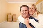 Happy Affectionate Couple in Room of New House With Only Boxes on the Floor.