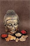 Chinese herbal medicine selection with buddha head over handmade lokta paper background.