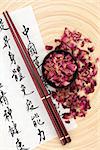 Chinese herbal medicine rose flower petals with  mandarin calligraphy script on rice paper describing the medicinal functions to maintain body and spirit health and balance body energy.