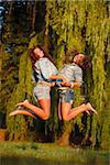 two teenage girls outdoors jumping holding hands