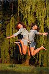 two teenage girls outdoors jumping full length