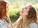close-up of two teenage girls outdoors in jeans wear happy laughing looking at each other