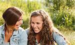 two girlfriends in jeans wear outdoors sitting  laughing