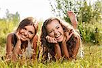 two girlfriends in T-shirts  lying down on grass laughing having good time