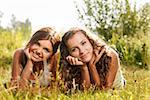 two girlfriends in T-shirts  lying down on grass having good time looking at camera