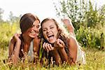 two girlfriends in T-shirts  lying down on grass laughing having good time