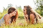 two girlfriends lying down on grass talking