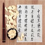 Ginger root chinese herbal medicine with mandarin calligraphy script on rice paper describing the medicinal functions to maintain body and spirit health and balance energy.